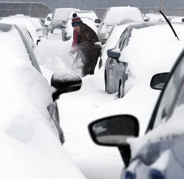Mary Mulloy of Strafford, Vt., works to dig her car out of the long term parking lot at the airport Monday, February 9, 2015, in Manchester, N.H. Mullor was returning from Salt Lake City, Utah where temperatures were in the 70's. (Photo by Jim Cole/AP Photo)