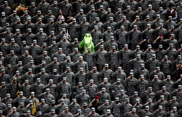A cadet dressed in an alligator mascot outfit joins fellow cadets in a salute during the national anthem before a football game between Army and Stanford in West Point, N.Y., on September 14, 2013. (Photo by Mike Groll/Associated Press)