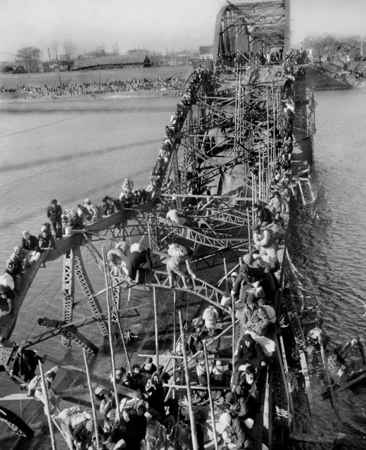 In this December 4, 1950 file photo, residents from Pyongyang, North Korea, and refugees from other areas crawl perilously over shattered girders of the city's bridge as they flee south across the Taedong River to escape the advance of Chinese Communist troops. Sports ties between the rival Koreas often mirror their rocky political ties. (Photo by Max Desfor/AP Photo)