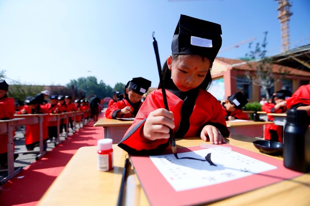 Primary school students write Chinese character “Ren”, meaning “human being”, during the First Writing Ceremony, a traditional education activity, on September 6, 2023 in Qingdao, Shandong Province of China. (Photo by VCG/VCG via Getty Images)