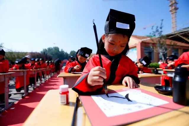 Primary school students write Chinese character “Ren”, meaning “human being”, during the First Writing Ceremony, a traditional education activity, on September 6, 2023 in Qingdao, Shandong Province of China. (Photo by VCG/VCG via Getty Images)