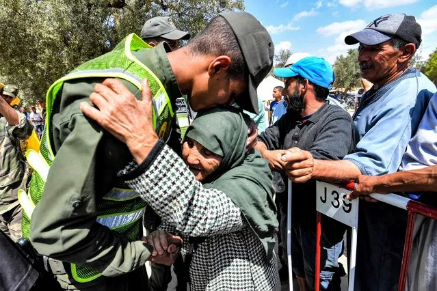 A member of Morocco's Auxiliary Forces embraces an elderly woman arriving to receive disaster relief aid from a distribution centre in the town of Amizmiz in al-Haouz province in the High Atlas mountains of central Morocco on September 12, 2023. Hopes dimmed on September 12 in Morocco's search for survivors, four days after a powerful 6.8-magnitude earthquake killed more than 2,900 people, most of them in remote villages of the High Atlas Mountains. (Photo by Fethi Belaid/AFP Photo)