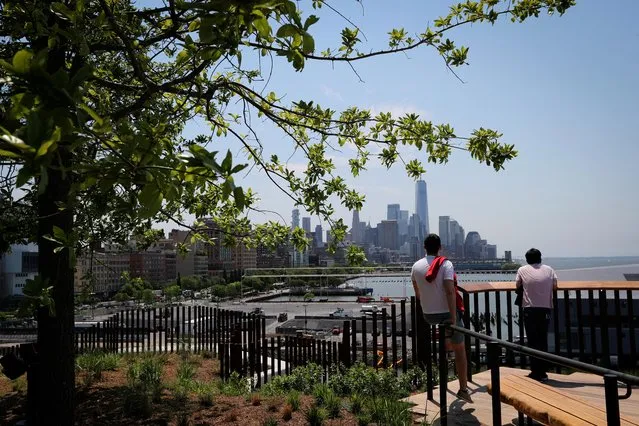 People look out at the skyline of lower Manhattan and One World Trade center tower from the peak of Little Island Park, almost three acres of new public park space which sits on stilts over the Hudson River and the remnants of Pier 54 in the larger Hudson River Park, on Manhattan's West Side, during the park's opening day in New York City, New York, U.S., May 21, 2021. (Photo by Mike Segar/Reuters)