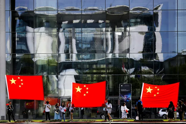 People show Chinese flags in front of the chancellery which is reflected in the facade of a German parliament building prior to the arrival of Chinese Premier Li Keqiang for a meeting with German Chancellor Angela Merkel in Berlin, Monday, July 9, 2018. (Photo by Markus Schreiber/AP Photo)