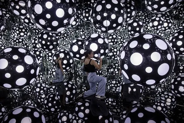 A woman takes photos at an art installation called Dots Obsession – Aspiring to Heaven’s Love by artist Yayoi Kusama’s with her signature polka dots and reflective mirrors in Hong Kong on August 4, 2023. (Photo by Isaac Lawrence/AFP Photo)