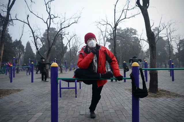 An elderly man wearing a mask exercises at a park in Beijing on December 20, 2016. Heavy smog suffocated northeast China for a fifth day on December 20, with hundreds of flights cancelled and road and rail transport grinding to a halt under the low visibility conditions. (Photo by Wang Zhao/AFP Photo)