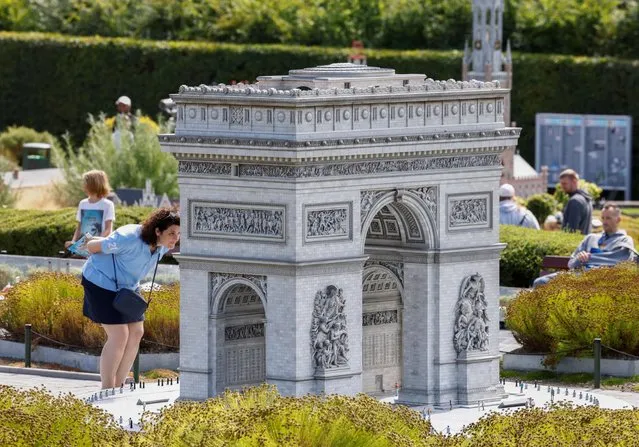 A visitor looks at a replica of Paris' Arc de Triomphe (triumphal arch) at Mini-Europe miniature park in Brussels, Belgium on July 27, 2022. (Photo by Yves Herman/Reuters)