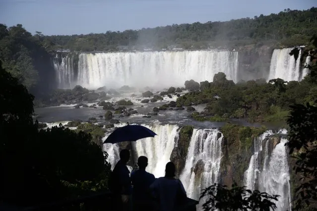 In this March 15, 2015 photo, tourists visit Iguazu Falls in Brazil. Spaniards came across the Iguazu Falls in 1541. The falls are part of the world's largest reservoir of fresh water, known as the Guarani Aquifer. They are in the middle of thick jungle that has more than 1,000 plant and hundreds of animal species. Millions of tourists visit the falls each year on both sides of the border. (Photo by Jorge Saenz/AP Photo)