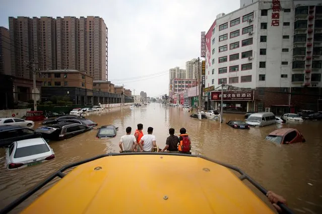 People ride a front loader as they wade through a flooded road following heavy rainfall in Zhengzhou, Henan province, China on July 22, 2021. (Photo by Aly Song/Reuters)