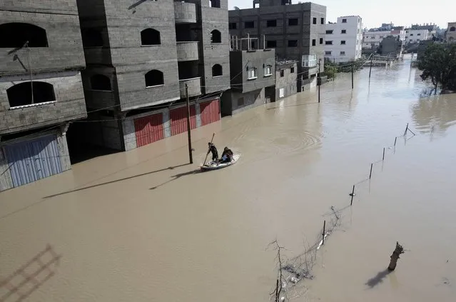 A Palestinian rescue member on a boat helps residents evacuate from a flooded area following heavy rains in Gaza City, Friday, December 13, 2013. Hundreds of houses were flooded following a rain storm in Gaza. Early snow has surprised many Israelis and Palestinians as a blustery storm, dubbed Alexa, brought gusty winds, torrential rains and heavy snowfall to parts of the Middle East. (Photo by Adel Hana/AP Photo)