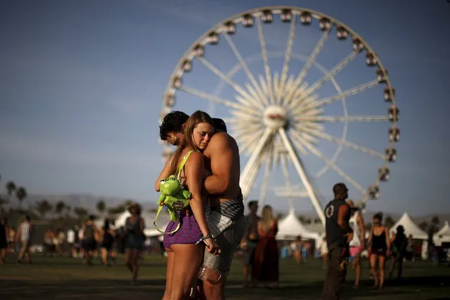 A couple hugs in front of the ferris wheel at the Coachella Valley Music and Arts Festival in Indio, California April 10, 2015. (Photo by Lucy Nicholson/Reuters)