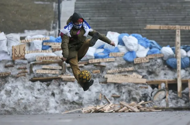 A Pro-European Union activist plays with the ball in front of barricades at the Independence Square in Kiev, Ukraine, Thursday, December 19, 2013. (Photo by Dmitry Lovetsky/AP Photo)
