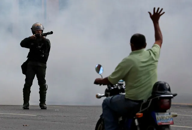 A man on a scooter lifts his hand opposite a security forces officer during a protest of opposition supporters against Venezuelan President Nicolas Maduro's government in Caracas, Venezuela, January 23, 2019. (Photo by Carlos Garcia Rawlins/Reuters)