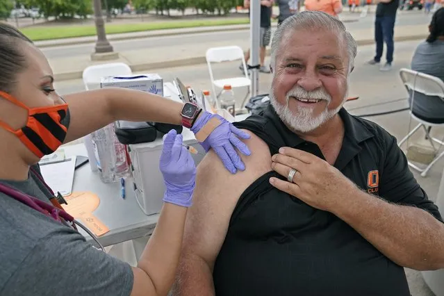 Mick Mitchell, of Edmond, Okla., smiles as he gets a COVID-19 vaccination shot from Dondie Hess, left, of the Oklahoma State University Center for Health Sciences, at a vaccination event before an NCAA college football game between Missouri State and Oklahoma State, Saturday, September 4, 2021, in Stillwater, Okla. Oklahoma State University announced that it will host COVID-19 vaccine clinics before home football games this fall to make it easier for students, fans and the community to receive a vaccine. (Photo by Sue Ogrocki/AP Photo)
