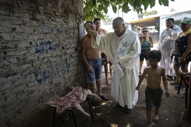 Catholic deacon Ramon Rodriguez blesses a pig prepped for grilling as part of the celebrations marking the feast day of Paraguay's patroness, Our Lady of Caacupe, commonly known as the “Blue Virgin”, in La Matanza district of Buenos Aires, Argentina, Thursday, December 8, 2022. (Photo by Rodrigo Abd/AP Photo)