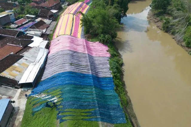 An aerial image shows fabric known locally as “beach fabric”, used to make Muslim women's garments, drying on a riverbank in Surakarta, Central Java, on January 4, 2024. (Photo by Garry Lotulung/AFP Photo)