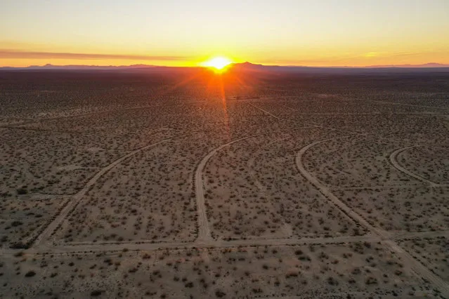 This aerial picture taken on October 2, 2021 shows the sun rising over a vast network of roads cut in the Mojave Desert, intended for a massive suburban paradise that was never built, in California City, California, approximately 100 miles (160 km) north of Los Angeles. (Photo by Robyn Beck/AFP Photo)
