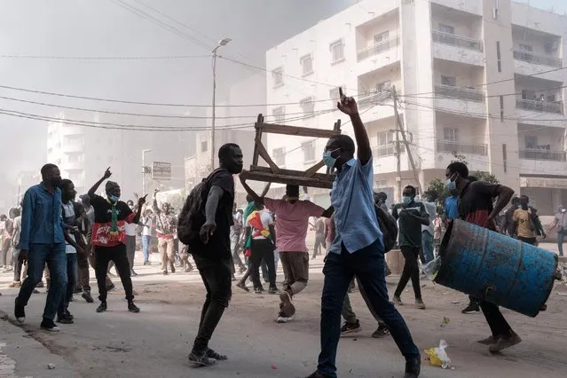 Protesters shout slogans and collect barrels and tables to burn during clashes with police on the sidelines of a protest against a last-minute delay of presidential elections in Dakar on February 9, 2024. On February 8, 2024, the parliament backed the president's sudden decision to postpone the February 25 election by 10 months, sparking a fierce opposition backlash and international concern. (Photo by Guy Peterson/AFP Photo)