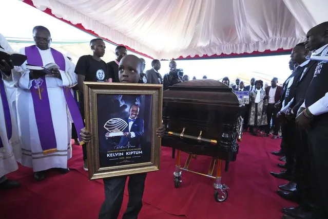 Caleb Kigen the son of marathon record holder Kelvin Kiptum, holds his late father's portrait ahead of his burial, in Elgeyo Marakwet, Kenya, Friday February 23, 2024. World marathon record holder Kelvin Kiptum was buried Friday following his death in a road accident, as Kenyans castigated the government for not doing enough to protect and support country's famed athletes. (Photo by Brian Inganga/AP Photo)