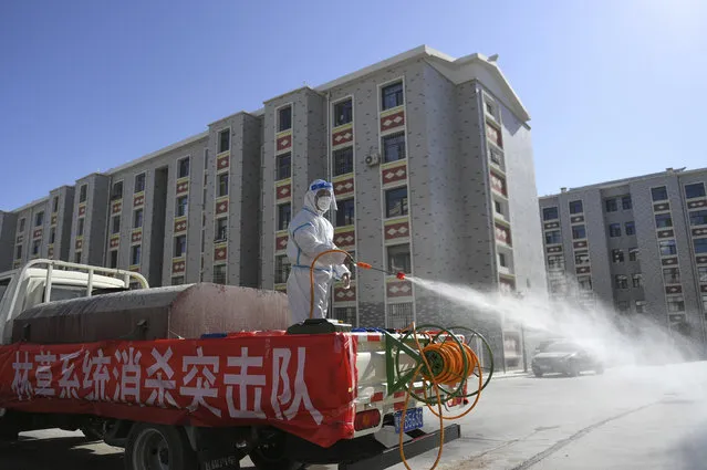 In this photo released by Xinhua News Agency, a worker disinfects a residential area in Dalai Hubu Township in Ejina Banner of Alxa League, in northern China's Inner Mongolia Autonomous Region, Wednesday, October 27, 2021. More than 2,000 tourists visiting China's Inner Mongolia region have been sent to hotels to undergo two weeks of quarantine following the detection of new cases of COVID-19 in the area. (Photo by Bei He/Xinhua via AP Photo)