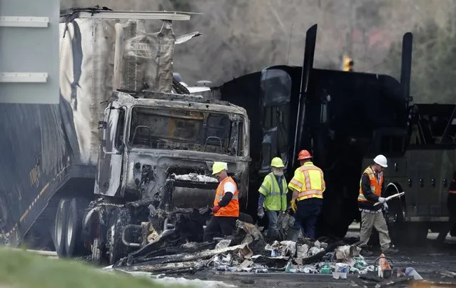 Workers clear debris from the eastbound lanes of Interstate 70 on Friday, April 26, 2019, in Lakewood, Colo., a deadly pileup involving semi-truck hauling lumber on Thursday. Lakewood police spokesman John Romero described it as a chain reaction of crashes and explosions from ruptured gas tanks. “It was crash, crash, crash and explosion, explosion, explosion”, he said. (Photo by David Zalubowski/AP Photo)