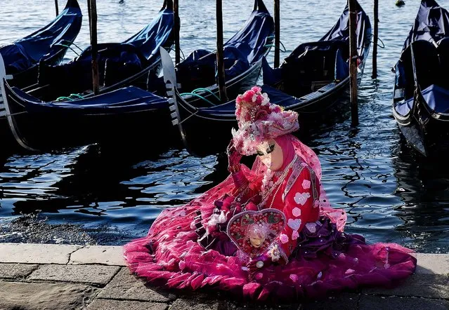 A woman dressed in Carnival costume poses in front of gondolas in Saint Mark's Square in Venice, on February 25, 2014. The 2014 Carnival of Venice will run from February 15 to March 4 and includes a program of gala dinners, parades, dances, masked balls and music events. (Photo by Marco Secchi/Getty Images)