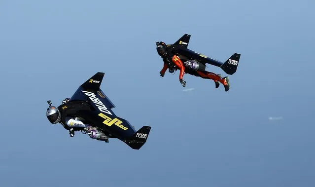 An aerial view taken from behind airplane's window glass shows Swiss pilot and aviation enthusiast Yves Rossy (L) known as the Jetman and French Vince Reffett (R) flying over the beach  in Dubai, United Arab Emirates on 12 May 2015. (Photo by Ali Haider/EPA)