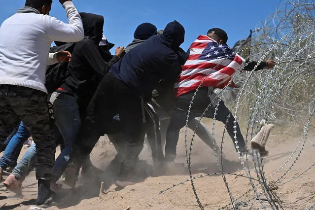 Migrants try to cross concertina wire at the U.S.-Mexico border near El Paso, Texas, on March 22, 2024. (Photo by Justin Hamel/Reuters)