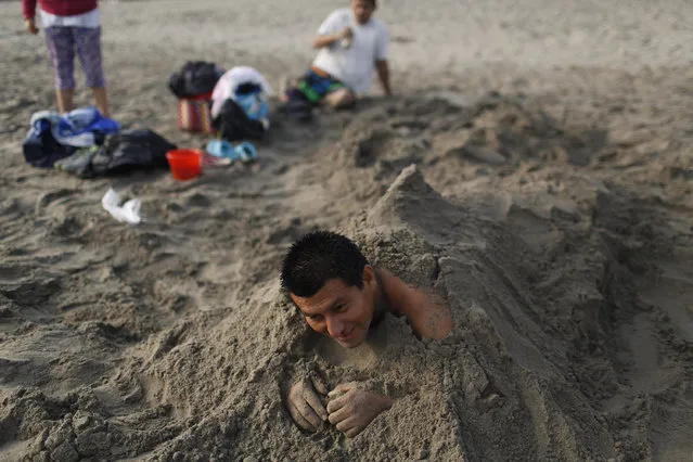 In this April 25, 2015 photo, Victor Villanueva rests in the sand on Fishermen's Beach during his therapeutic session of “sand therapy” on the coast of the Pacific Ocean in Lima, Peru. Villanueva is one of many along Lima's coast practicing thalassotherapy, in search of relief from the ailments doctors have been unable to cure. (Photo by Rodrigo Abd/AP Photo)