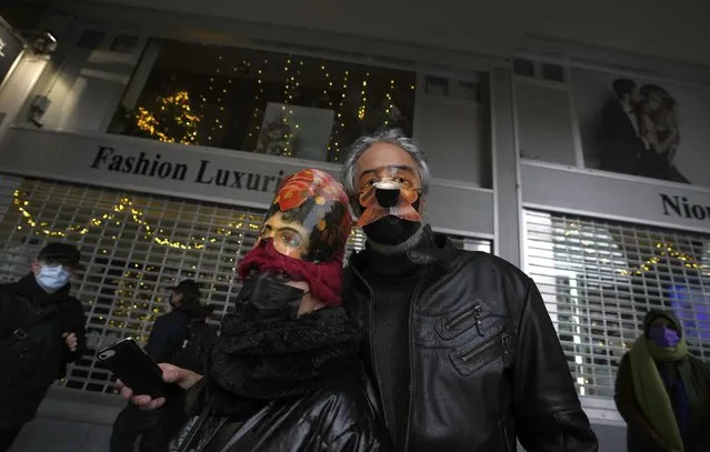 Two artists wear masks as they participate in a demonstration of people in the arts in Brussels on Sunday, December 26, 2021. Belgian performers, cinema operators, event organizers and others joined together Sunday to protest the government's decision to close down the country's cultural life to stem the spread of the surging omicron virus variant. Gluhwein refers to a common drink which is served at Christmas markets. (Photo by Virginia Mayo/AP Photo)