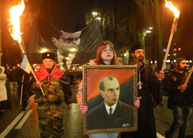 Activists of various nationalist parties carry torches and a portrait of Stepan Bandera during a rally in Kyiv, Ukraine, Saturday, January 1, 2022. The rally was organized to mark the birth anniversary of Stepan Bandera, founder of a rebel army that fought against the Soviet regime and who was assassinated in Germany in 1959. (Photo by Efrem Lukatsky/AP Photo)