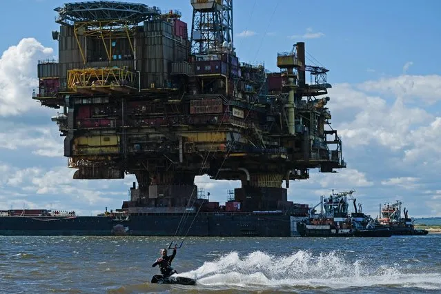 Kitesurfer Terry Bennions surfs in front of the Brent Bravo topside oil platform as it is transported on the barge Iron Lady into the mouth of the River Tees on route to the Able UK Seaton Port site for decommissioning on June 20, 2019 in Teesport, England. The 24,800 tonne oil platform was transported to an area off the Hartlepool coast by the largest heavy lift vessel ever built, Pioneering Spirit from the Shell Brent oil fields that are situated 115 miles north-east of Lerwick in Scotland. After arriving off the coast of Hartlepool the 410ft high platform was transferred to the barge to be towed into the mouth of the River Tees. This is the second oil platform to be removed from the Shell Brent oil field with the sister platform, Brent Delta decommissioned at the same site in 2017. Once at the Able UK site Brent Bravo will be broken down with some parts being re-sold and the rest scrapped and re-cycled. At its peak in 1982 the four Shell platforms in the Brent field were producing more than half a million barrels of oil a day. Production at the field was stopped in 2011. (Photo by Ian Forsyth/Getty Images)