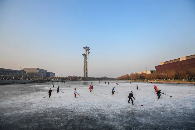 A group of people play ice hockey on the frozen river near the The National Stadium Bird's Nest on January 05, 2022 in Beijing, China. The 2022 Beijing Winter Olympic Games will be open in 30 days. (Photo by Di Yin/Getty Images)