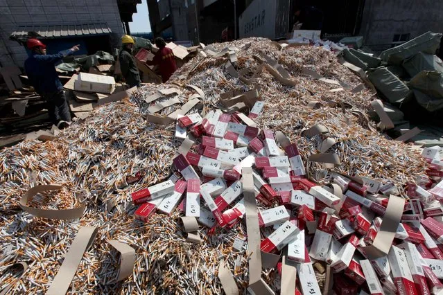 This photo taken on March 14, 2017 shows workers piling up fake and inferior cigarettes before being destroyed to mark World Consumer Rights Day in Xuchang, central China's Henan province. (Photo by AFP Photo/Stringer)