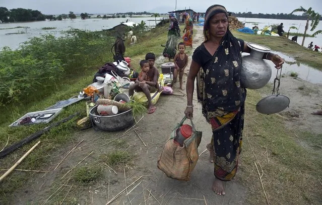 An Indian flood affected woman carries her belongings on an embankment to take shelter in Pabhokathi village east of Gauhati India, Monday, July 15, 2019. After causing flooding and landslides in Nepal, three rivers are overflowing in northeastern India and submerging parts of the region, affecting the lives of more than 2 million, officials said Monday. (Photo by Anupam Nath/AP Photo)