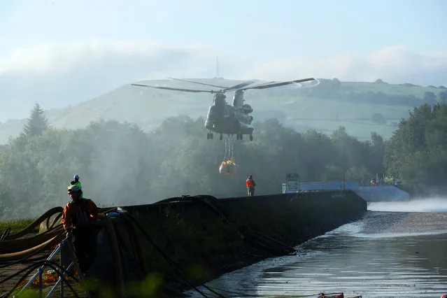 An RAF Chinook helicopter flies in sandbags to help repair the dam at Toddbrook reservoir near the village of Whaley Bridge in Derbyshire on August 2, 2019, after it was damaged by heavy rainfall. (Photo by Yui Mok/PA Images via Getty Images)