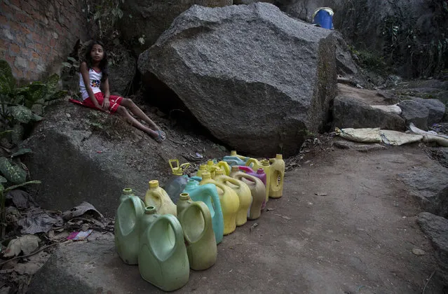 An Indian girl waits for the arrival of water supply at a public tap next to plastic cans lined up by others for collecting drinking water in a hill area on the eve of World Water Day in Gauhati, India, Tuesday, March 21, 2017. There is no direct supply of potable water at homes in most of the poor neighborhoods in the country and people have to depend on regulated supply of water from public taps erected on roadsides, with a single tap catering to hundreds of households. (Photo by Anupam Nath/AP Photo)