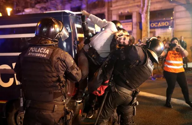 A riot police officer looks on as a separatist demonstrator is detained during a protest after a verdict in a trial over a banned independence referendum in Barcelona, Spain, October 15, 2019. Protesters and police clashed in Barcelona in a second day of protests, after the Supreme Court sentenced nine separatist leaders to nine to 13 years in jail over their role in a failed bid to break away from Spain in 2017. The clashes are a challenge for the regional, pro-independence authorities and the central government in Madrid, both of which are facing a fragmented political landscape and an economic slowdown. (Photo by Jon Nazca/Reuters)