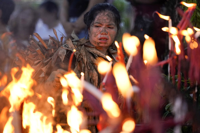 A devout Catholic lights candles outside the church of Saint John the Baptist during the mud festival at Bibiclat, Nueva Ecija province, northern Philippines, Monday, June 24, 2024. (Photo by Aaron Favila/AP Photo)