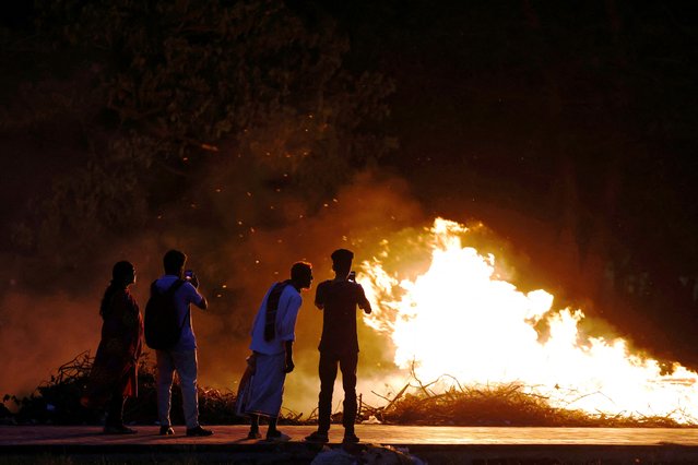 People take pictures in front of a fire that was lit on waste at a park in Dhaka, Bangladesh on June 3, 2024. (Photo by Mohammad Ponir Hossain/Reuters)