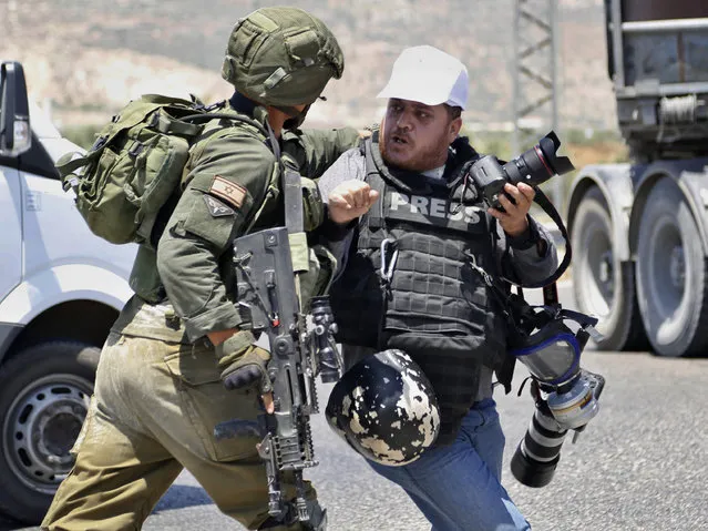 Israeli soldier pushes a Palestinian photojournalist during protest in solidarity with Palestinian prisoners on hunger strike in Israeli jails near them near the settlement of Shavei Shamron near the West Bank city of Nablus, Tuesday, May 16, 2017. (Photo by Majdi Mohammed/AP Photo)
