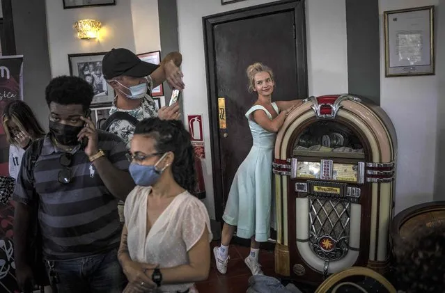 A tourist poses for a souvenir photo next to a Wurlitzer-style jukebox as journalists attend a press conference at the National Hotel in Havana, Cuba, February 9, 2022. (Photo by Ramon Espinosa/AP Photo)