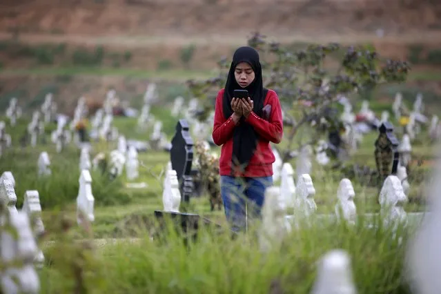 A Muslim woman prays at the grave of a relative at a cemetery reserved for those who died of COVID-19, in Medan, North Sumatra, Indonesia, Thursday, March 31, 2022. Prior to the holy fasting month of Ramadan that is expected to begin on Sunday, Muslims followed local tradition to visit cemeteries to pray for their deceased loved ones. (Photo by Binsar Bakkara/AP Photo)