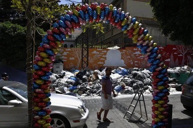 A man passes by a pile of garbage on a Beirut street in Lebanon on Sunday, July 26, 2015. Protesters have closed the highway linking Beirut with southern Lebanon over the country's trash crisis. The closure of the vital highway in the coastal town of Jiyeh on Sunday comes amid reports that the government plans to move trash piled on the streets of Beirut to the Kharoub region south of the capital. (Photo by Hassan Ammar/AP Photo)