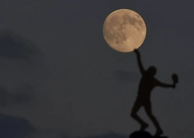 The moon rises above the weather vane at the All England Lawn Tennis and Croquet Club which hosts the Wimbledon Tennis Championships in London, June 30, 2015. (Photo by Toby Melville/Reuters)