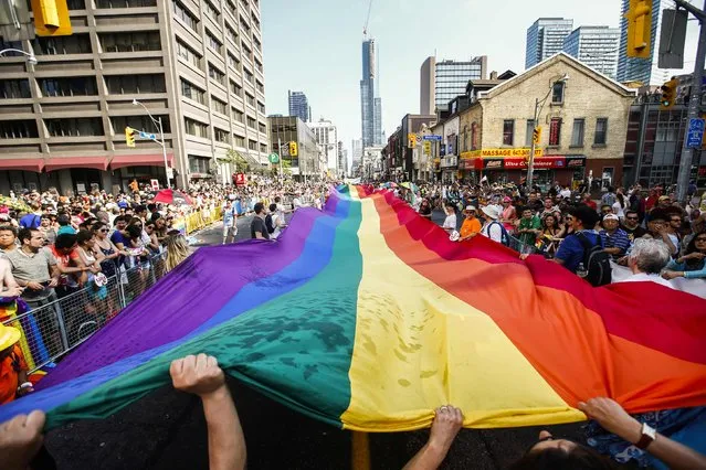 Revellers hold a giant pride flag during the “WorldPride” gay pride Parade in Toronto, June 29, 2014. Toronto is hosting WorldPride, a week-long event that celebrates the lesbian, gay, bisexual and transgender (LGBT) community. (Photo by Mark Blinch/Reuters)