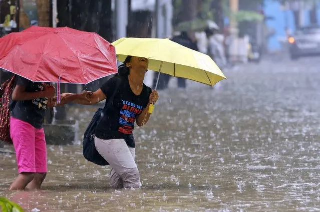 A girl laughs as she wades through knee-deep water in the rain in Mumbai, India, Wednesday, July 9, 2014. Waterlogging caused by incessant rainfall disrupted road traffic in several areas on the commercial capital. (Photo by Rajanish Kakade/AP Photo)