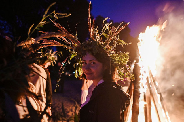 A woman wearing a wreath attends the Kupala night celebrations near Yagidne village, Chernihiv region, on July 8, 2023 after volunteering to clear debris from destroyed buildings in the region, amid the Russian invasion of Ukraine. (Photo by Genya Savilov/AFP Photo)