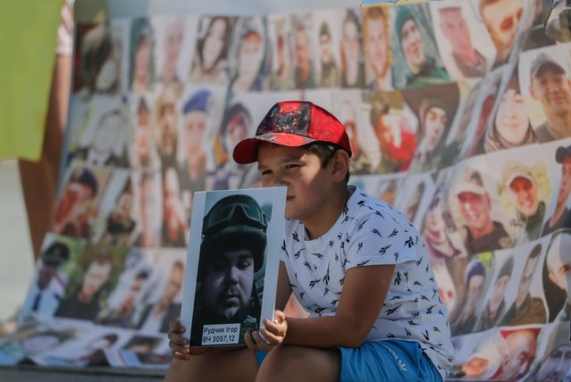 A boy holds a picture as relatives and friends of Ukrainian missing soldiers and prisoners of war attend a protest on the Independence Square in Kyiv, Ukraine, 04 August 2023. Ukrainians call the authorities to find and return their relatives from Russian captivity. Russian troops entered Ukrainian territory on 24 February 2022, starting a conflict that has provoked destruction and a humanitarian crisis. (Photo by Sergey Dolzhenko/EPA/EFE)