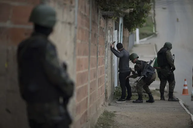 Air force personnel pat down a resident at the Caramujo slum in Niteroi, Brazil, Wednesday, August 16, 2017. (Photo by Leo Correa/AP Photo)